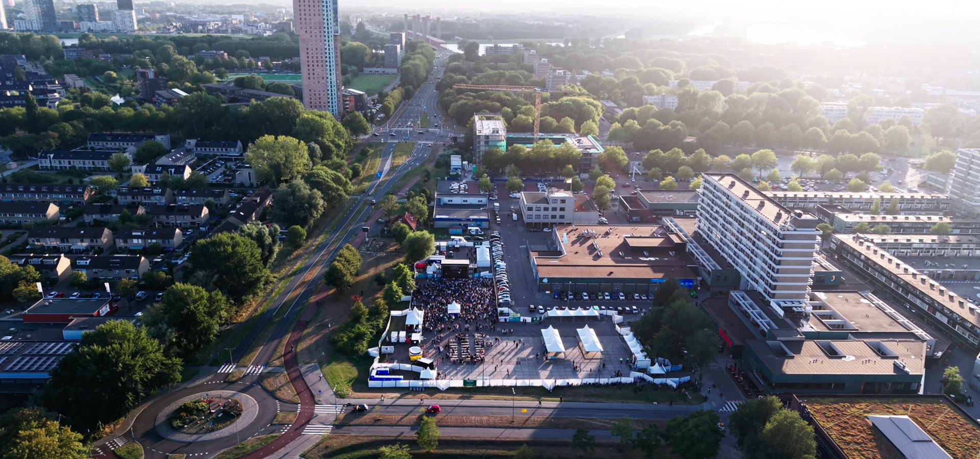 Luchtfoto van de Participarade in Hoogvliet, met bezoekers, tenten en het podium tussen de woonwijk.